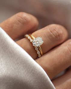 a woman's hand with a diamond ring on top of her finger and a white cloth