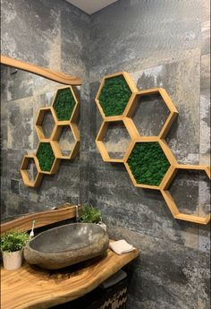 the bathroom is decorated with green moss and hexagonal wooden shelves on the wall