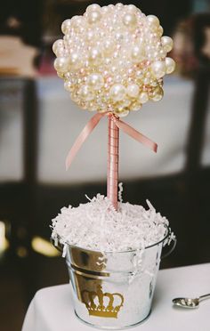 a flower pot filled with white pearls and a pink ribbon tied to it's top