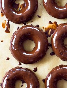 six chocolate donuts with nuts on top of them sitting on a baking sheet, ready to be eaten