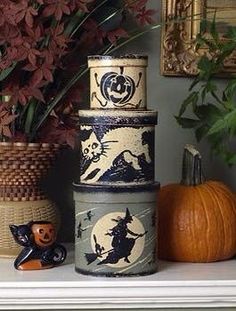 a stack of ceramic containers sitting on top of a table next to a pumpkin and potted plant