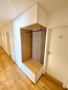 an empty room with wooden flooring and white cupboards on the wall next to it