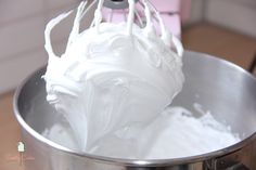 a metal bowl filled with white frosting on top of a table