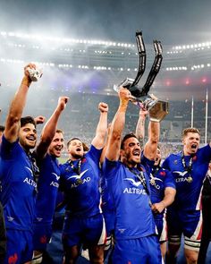 rugby players holding up their trophy in the air