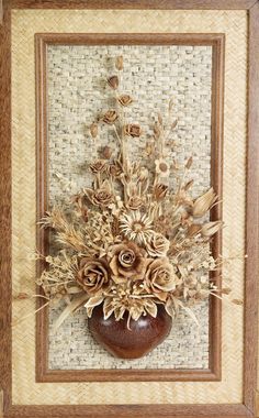 a vase filled with dried flowers on top of a wooden table next to a wall