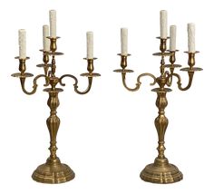 two brass candelabra with white candles on each candle holder, one is turned upside down