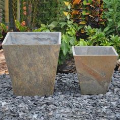 two square planters sitting on top of a pile of rocks next to each other