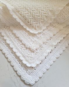 three crocheted afghans are stacked on top of each other, one is white