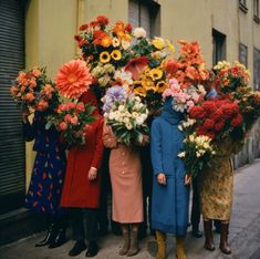 four women standing in front of a building with flowers on their heads