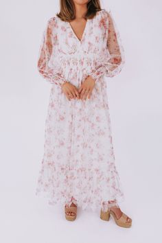 Get ready to turn heads with the Romance In The Air Dress! This off-white dress boasts a stunning floral print and a flattering V neckline. The smocking around the waist and sleeve cuffs creates a perfect fit, while the long sheer sleeves add an elegant touch. With a maxi length and a tier on the skirt, this dress is sure to make you feel like a romantic dream! Details Off white dress with floral print V neckline Smocking around waist and sleeve cuffs Fully lined Long, sheer sleeves Maxi length Feminine Midi Dress With Smocked Cuffs For Brunch, White Feminine Floral Dress With Smocked Bodice, White Floral Dress With Smocked Bodice, White Flowy Dress With Elastic Sleeves, Flowy White Dress With Elastic Sleeves, Flowy White Dresses With Elastic Sleeves, White Dress With Elastic Sleeves And Flowy Fit, Midi Dress With Smocked Cuffs For Garden Party, Feminine Summer Dress With Smocked Cuffs