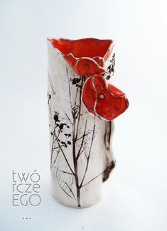 a white vase with two red flowers on it's side and the bottom part of the vase is made out of ceramic