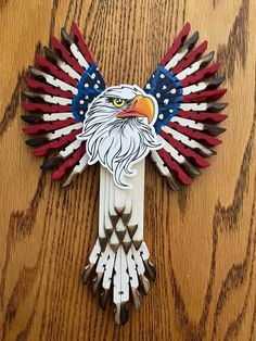 an eagle made out of toothpicks on top of a wooden table with red, white and blue feathers