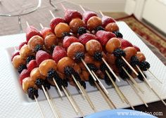 strawberries and blackberries are arranged on skewers