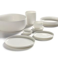 white dishes and cups are arranged on the table top, with one empty bowl in the middle