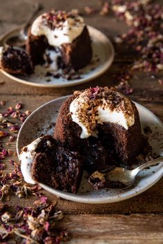 two white plates topped with desserts on top of a wooden table next to dried flowers