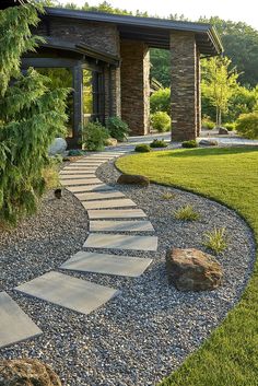 a stone path in the middle of a garden with rocks and grass around it, leading to a covered patio