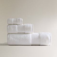 four white towels stacked on top of each other in front of a light colored wall