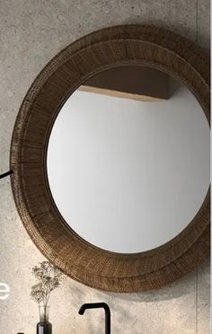 a round mirror hanging on the side of a wall next to a sink and faucet