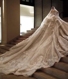 a woman in a wedding dress standing on some stairs with her back to the camera