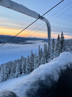 a ski lift going up the side of a mountain covered in snow and surrounded by trees