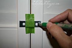 a person is holding a green piece of paper near a white door with two holes in it