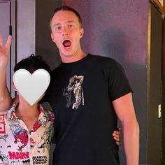 a man and woman standing next to each other with a heart shaped object in front of them