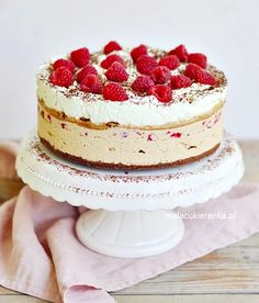 a white cake with raspberries on top