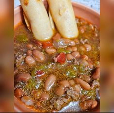 two burritos sitting on top of a bowl filled with beans