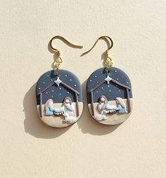 a pair of earrings with the nativity scene painted on them