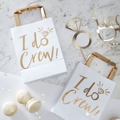 two bags with i do crew on them next to gold confetti and other decorations