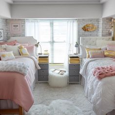 two beds in a bedroom with pink and yellow comforters on the covers, white rugs and pillows