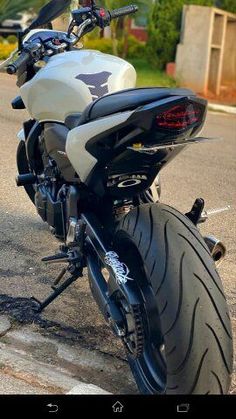 a white and black motorcycle parked on the side of the road in front of a house