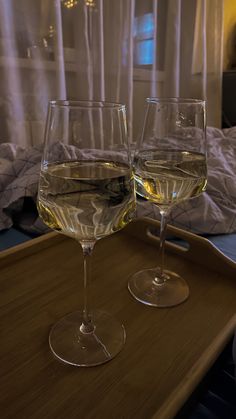 two wine glasses sitting on top of a wooden tray