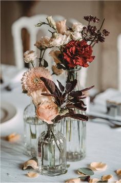 two vases filled with flowers sitting on top of a white tablecloth covered table