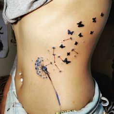 a woman's stomach with a dandelion tattoo on her side and butterflies flying around it