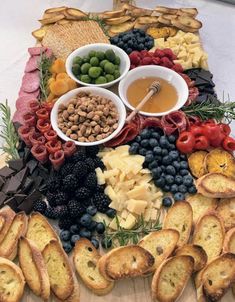 a platter with breads, grapes, olives and other foods