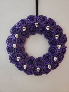 a purple wreath with skulls and roses on it hanging from the wall in front of a door