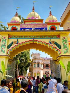 people are standing in front of the entrance to an ornate building that is painted yellow and pink