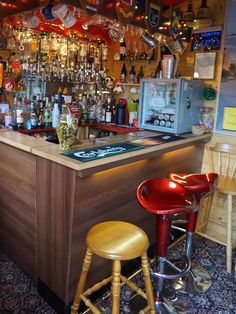 a bar with two stools in front of it and many bottles on the wall