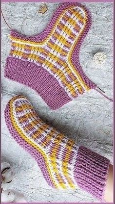 a knitted pair of socks sitting on top of a wooden floor next to a plant