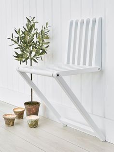 a white chair sitting next to a potted plant on top of a wooden floor