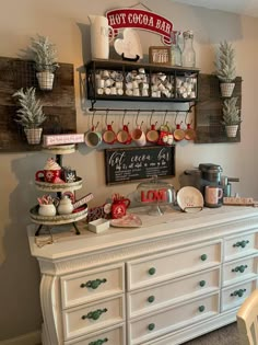 a white dresser topped with lots of pots and pans next to a wall mounted sign