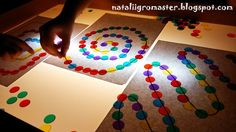 a child is playing with colored circles on the paper and light up their fingers to make them look like they are doing something