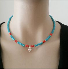 a woman wearing a necklace with a hamsa charm on it's clasps