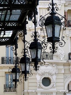 an old fashioned street light in front of a white building with ornate ironwork on it