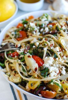 a white bowl filled with pasta and veggies on top of a striped table cloth