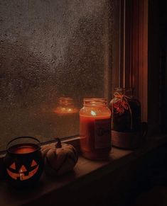 two pumpkins sitting on a window sill next to a candle and some jars