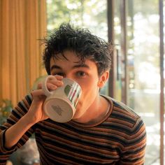 a young man drinking from a coffee cup