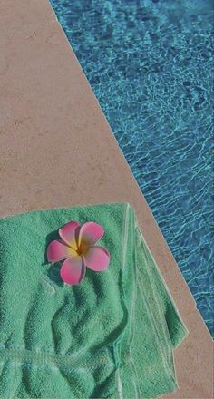 a towel with a flower on it next to a swimming pool