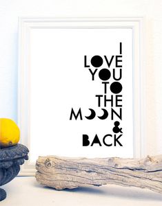 i love you to the moon and back print in black on a white wall next to driftwood